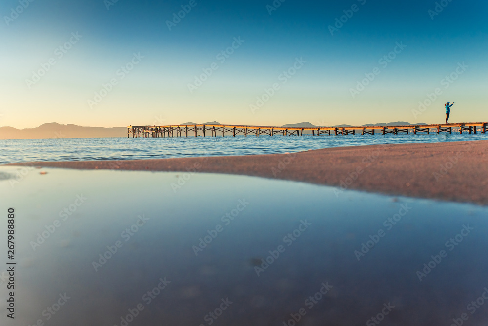 Man on the pier by the sea. Beautiful warm sunrise light. Summer vacation concept photo