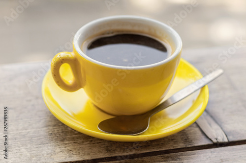 Chipped yellow coffee cup and saucer on a wooden table, closeup with a shallow depth of field