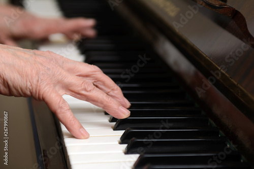 Hands of an elderly woman over the keys of the piano. Concept - hobby in retirement