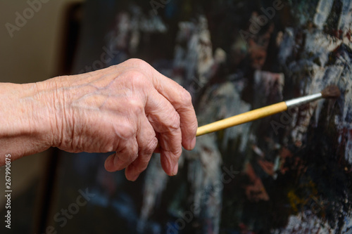 In the hand of an elderly woman artistic brush, which she paints a picture © yuryastankov
