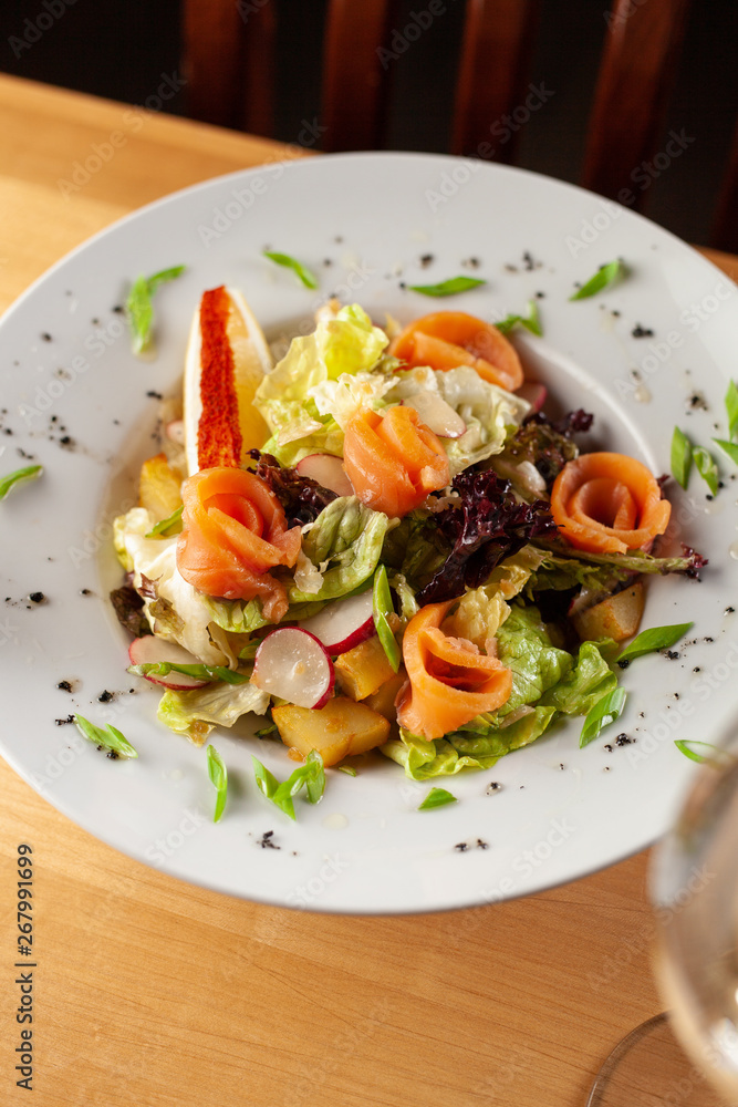 Fresh trout salad with greens and herbs on a white plate Fresh trout salad with greens and herbs on a white plate