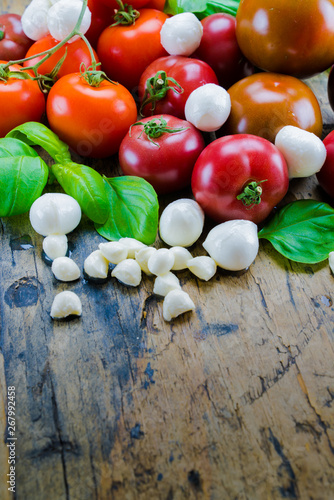 tasty colorful organic food ingredients for tomato mozzarella salad on a rustic wooden table