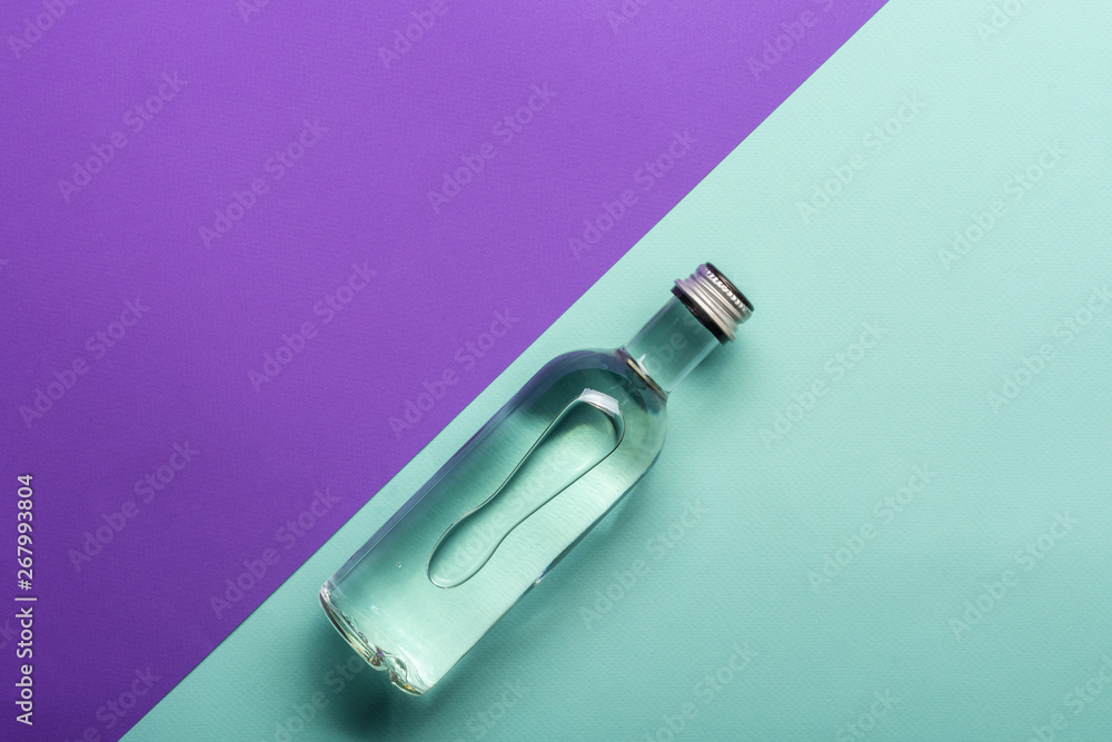transparent wineglass and bottle with water on bright purple and azure background transparent wineglass and bottle with water on bright purple and azure background