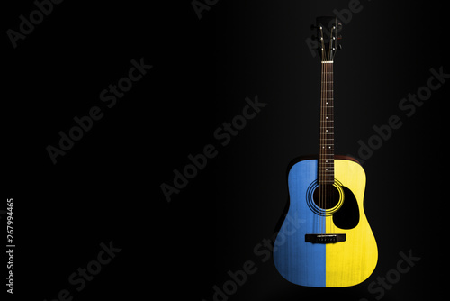 Acoustic concert guitar with a drawn flag Ukraine, on a dark background, as a symbol of national creativity or folk song.