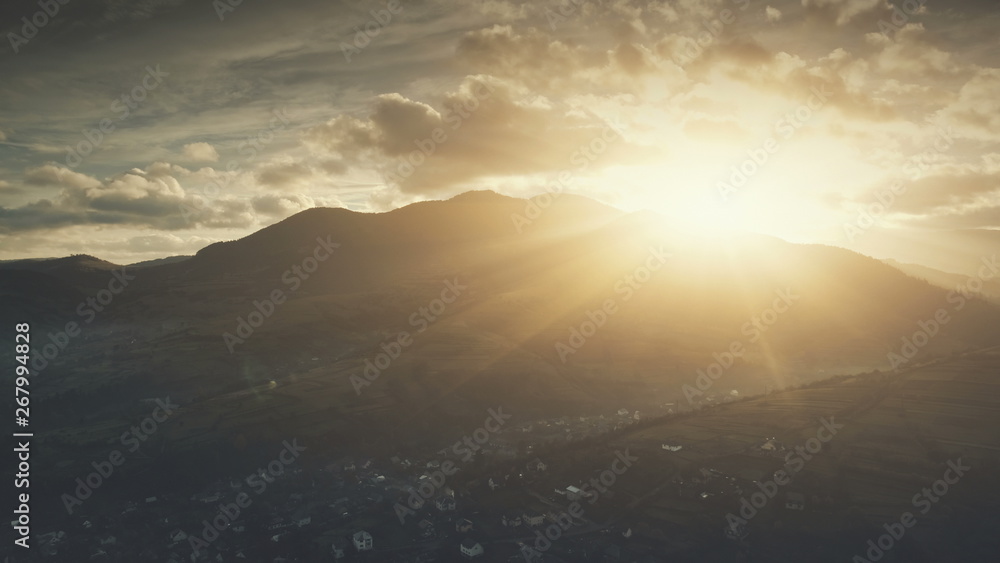 Epic Sunrise Sun Flare Mountain Village Aerial View. Morning Highland Suburban Town Scenery Hill Countryside Overview. Clouds Fast Flow in Sky. Copter Rise Up. Timelapse Drone Flight