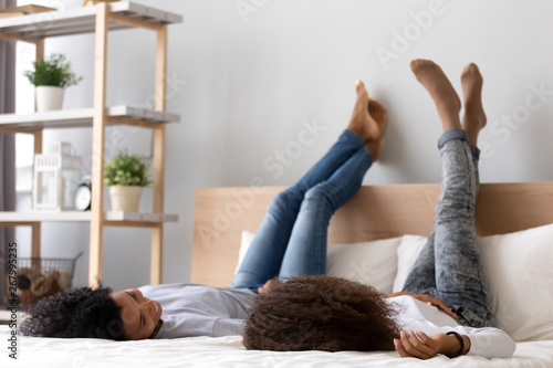 African American mother and daughter lying on bed and talking