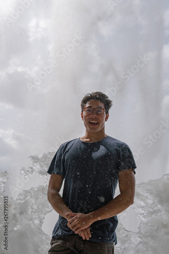 Man standing on ice in front of a waterfall.