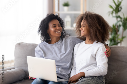 African American mother and daughter using laptop, having fun together