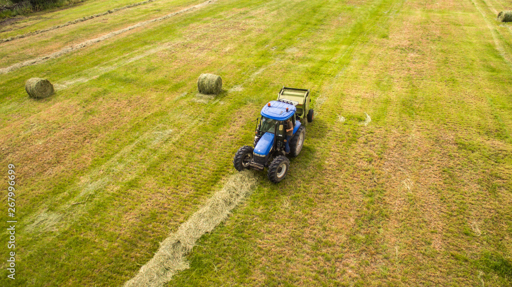 bird eye of Man at work on the tractor with hay baler