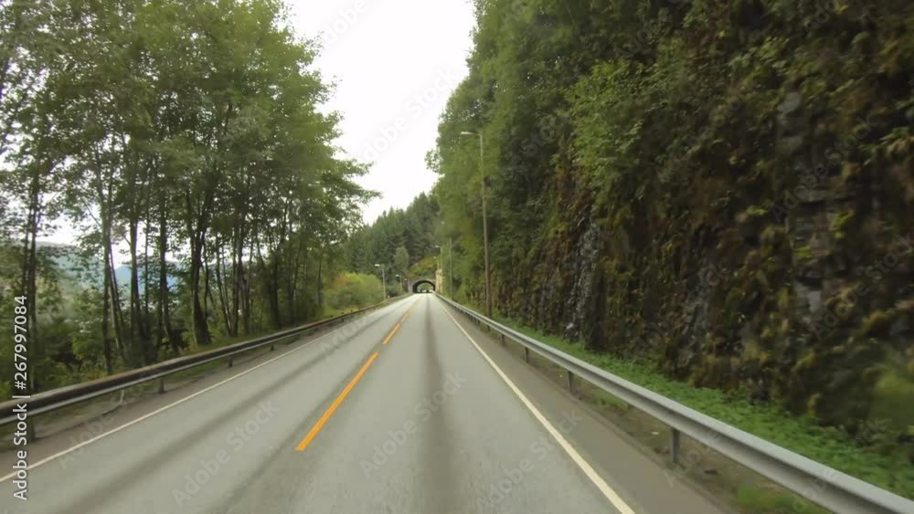 A road with many curves runs through a wooded area in Norway. Amazing realtime countryside view from a tour bus. A road with many curves runs through a wooded area in Norway. Amazing realtime countryside view from a tour bus.