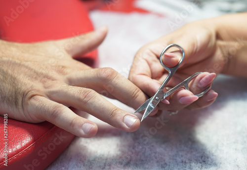 Nail scissors in the hands of a professional. Salon Crassot. man hands in the process of work. Fashionable beauty theme. Stock photo