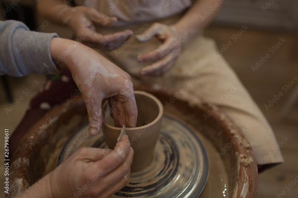 Fototapeta premium Potter working on potters wheel making ceramic pot from clay in pottery workshop