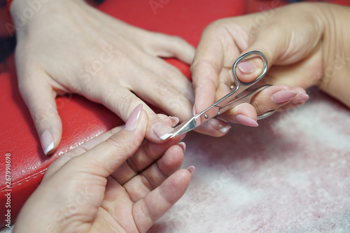 Nail scissors in the hands of a professional. Salon Crassot. Woman's hands in the process of work. Fashionable beauty theme. Stock photo