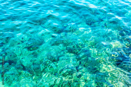 Transparent turquoise sea water with sun glare, background.