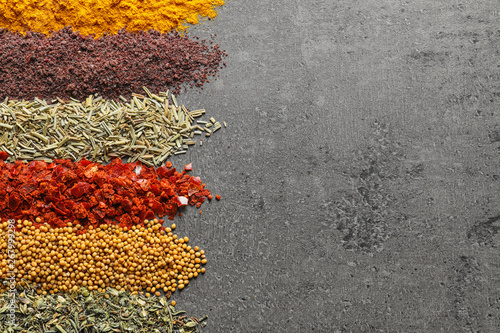 Rows of different aromatic spices on gray  background, top view with space for text