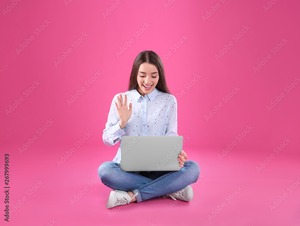 Naklejka premium Woman using laptop for video chat on color background