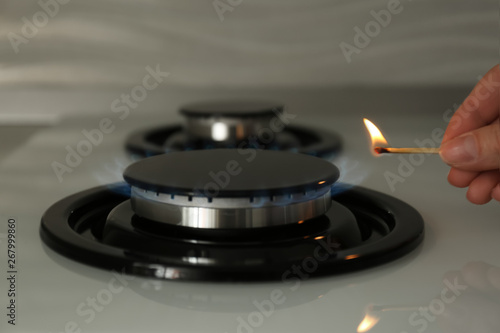 Woman lighting gas stove with match, closeup
