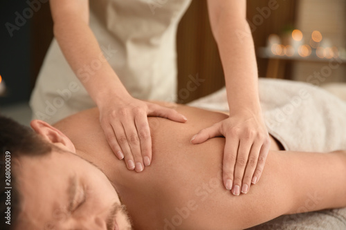 Handsome man receiving back massage in spa salon, closeup