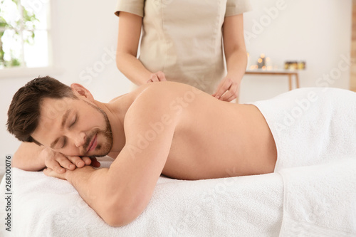 Handsome man receiving back massage in spa salon