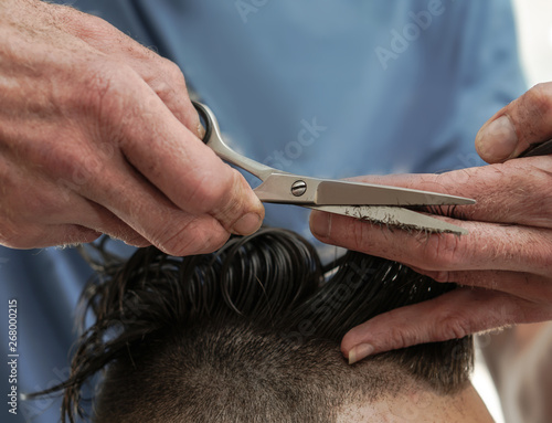 Haircutting process in the hairdresser. man in the salon smoothes his hair. Hands with scissors. Stock photos for design