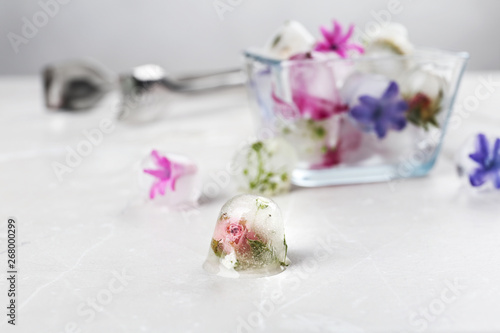 Composition with floral ice cubes on table, space for text