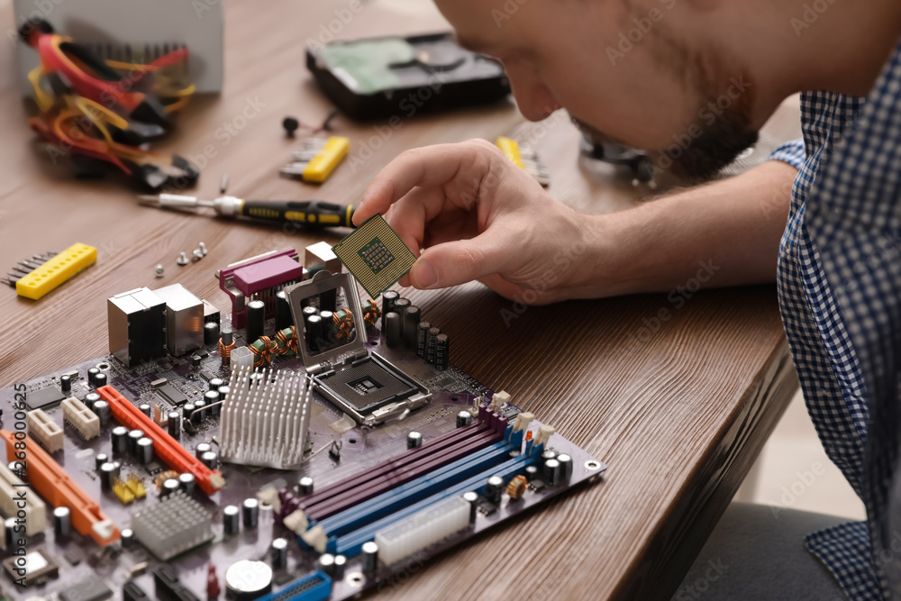 Male technician repairing motherboard at table, closeup Male technician repairing motherboard at table, closeup
