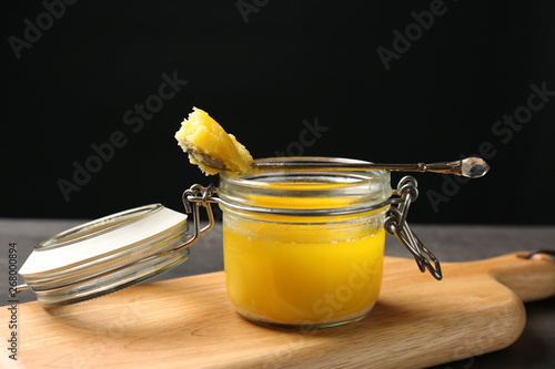 Jar and spoon with clarified butter on wooden board