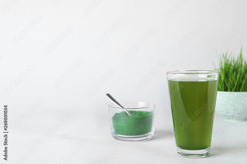 Glass of spirulina drink and bowl with powder on white background. Space for text Glass of spirulina drink and bowl with powder on white background. Space for text
