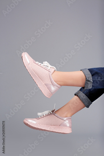 Woman in stylish sport shoes on grey background
