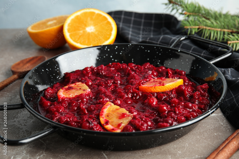 Tasty cranberry sauce with citrus fruit slices in pan on table Tasty cranberry sauce with citrus fruit slices in pan on table
