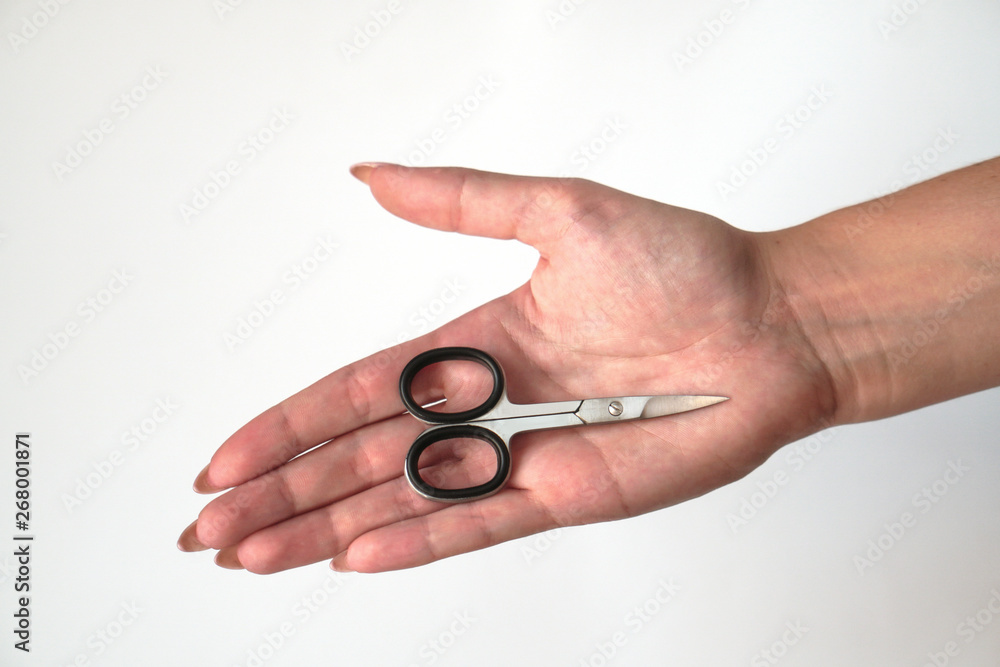 Manicure scissors on the hand of a young girl. Female beauty and body care. Stock photo Manicure scissors on the hand of a young girl. Female beauty and body care. Stock photo