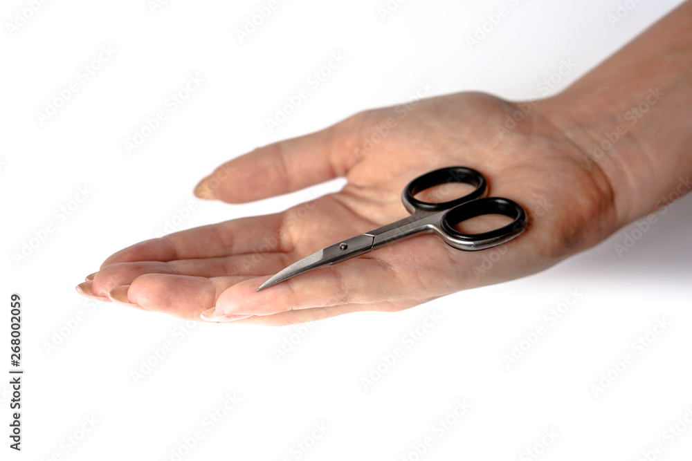 Manicure scissors on the hand of a young girl. Female beauty and body care. Stock photo Manicure scissors on the hand of a young girl. Female beauty and body care. Stock photo