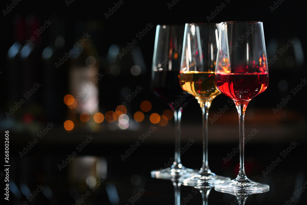 Row of glasses with different wines on bar counter against blurred background. Space for text