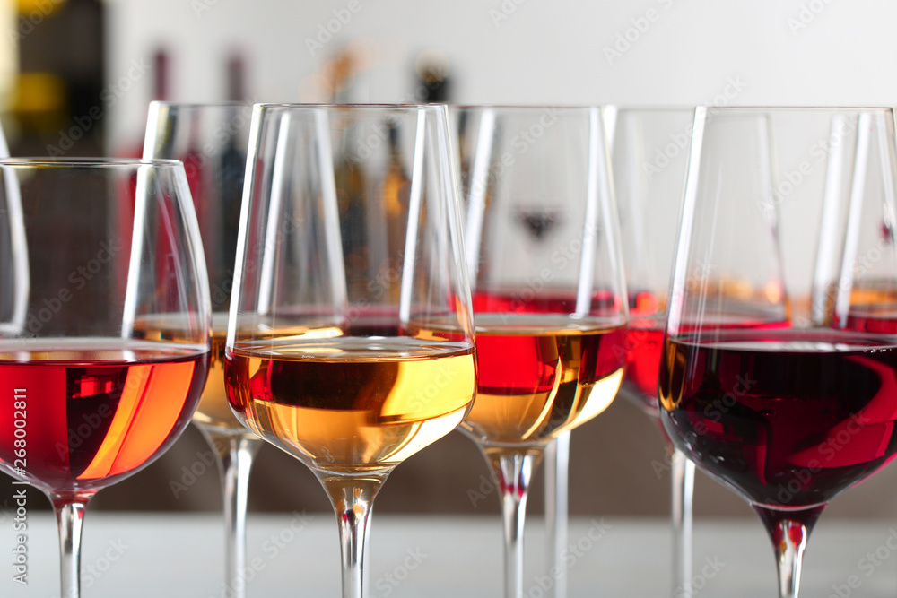 Glasses with different wines on blurred background, closeup Glasses with different wines on blurred background, closeup