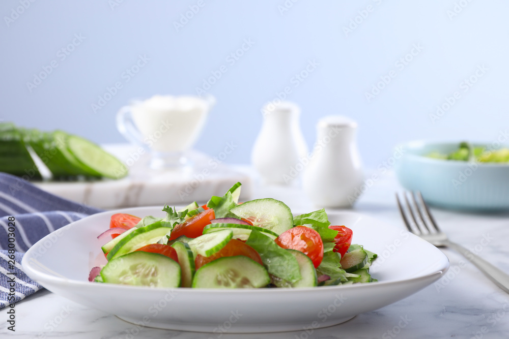 Plate of vegetarian salad with cucumber, tomato, lettuce and onion served on table