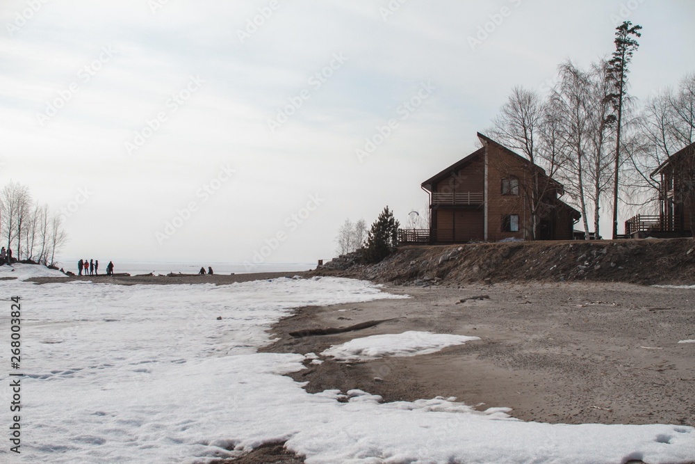 The concept of a country holiday. Wooden house on the lake covered with ice and snow