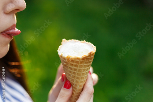 Young beautiful girl with long flowing hair eat ice cream. Bright sunny day. Natural background. Soft focus. Ice cream close-up