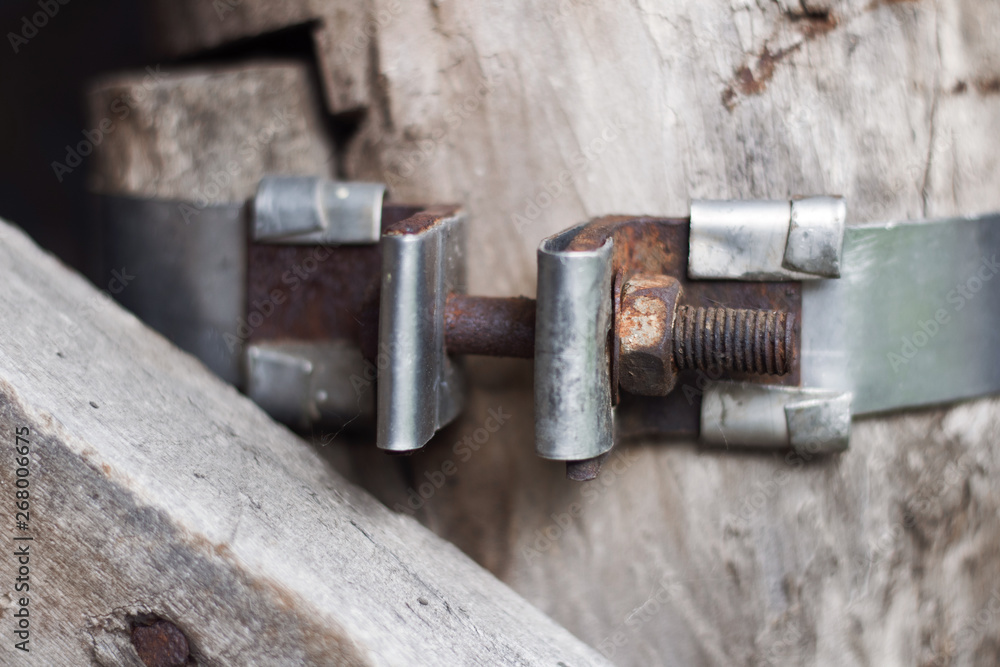 old metal part with screw connection on wooden wall background old metal part with screw connection on wooden wall background