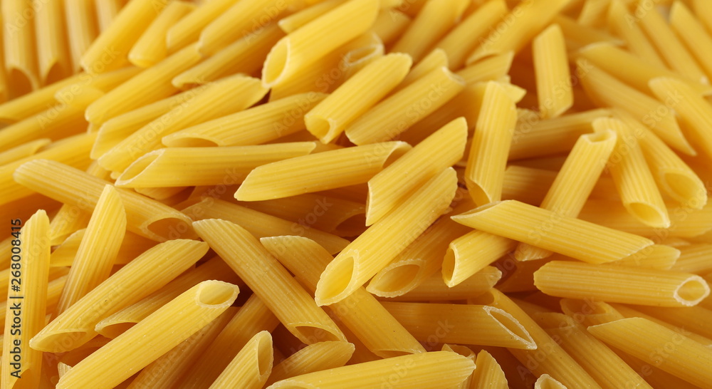 Penne rigate pasta pile background and texture, side view Penne rigate pasta pile background and texture, side view