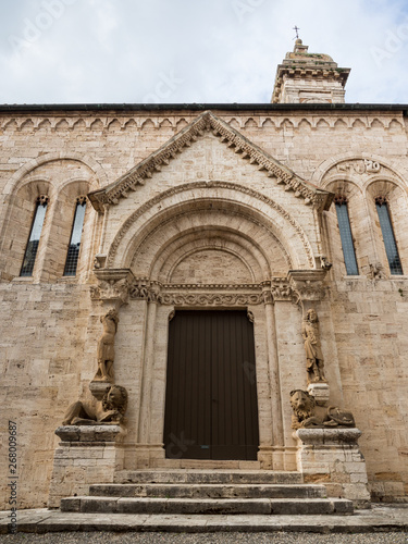 The carved stone entrance with columns of statues and stone lions of the abbey of San Quirico d'Orcia, Italy,