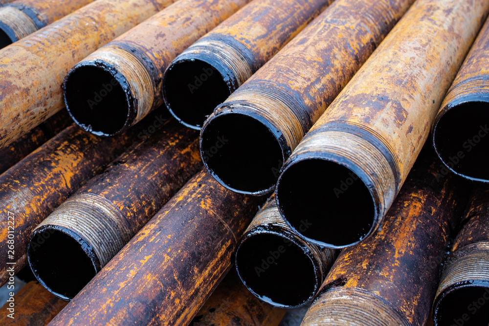 Salvaged pipes and casings are lined up on racks in storage on a California oil lease. Drill pipes with oil drops. Salvaged pipes and casings are lined up on racks in storage on a California oil lease. Drill pipes with oil drops.