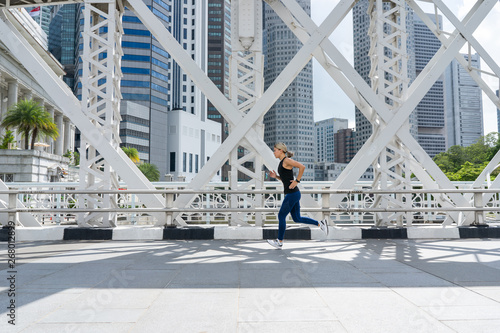 Canvas Print Young asian woman runner running on city bridge road