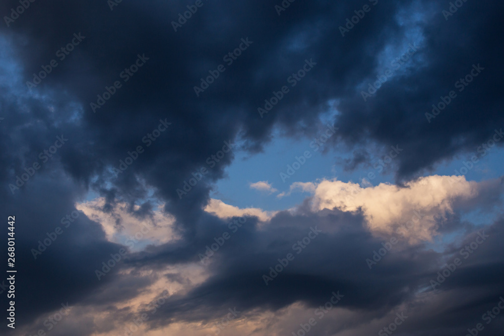 Epic dramatic storm dark clouds against blue sky background. Darkness and light, heaven