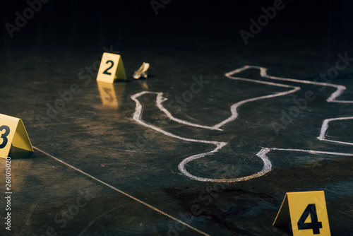 Foto selective focus of chalk outline and evidence markers at crime scene