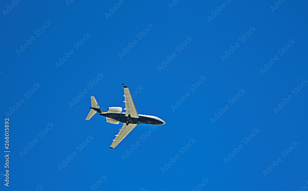 A Blue and White Passenger Jet from Below Under Blue Skies A Blue and White Passenger Jet from Below Under Blue Skies