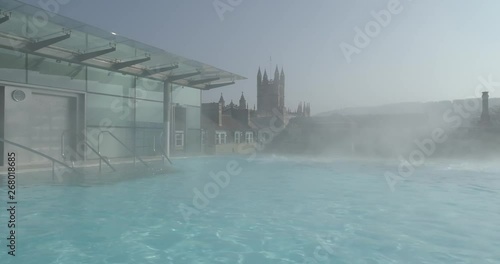 Stablised tracking shot from changing area to rootop thermal pool in historic Roman city of Bath Spa in England with Bath Abbey cityscape in the background photo