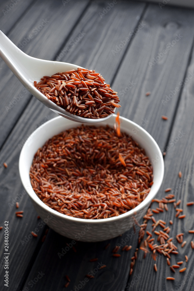 hand holdind a spoon with red rice pouring