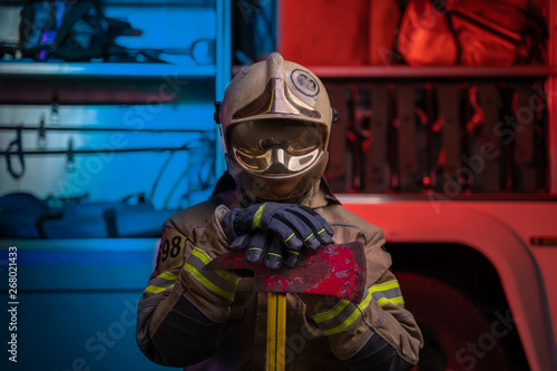Photo of man fireman in helmet and helmet with pick on background of fire truck
