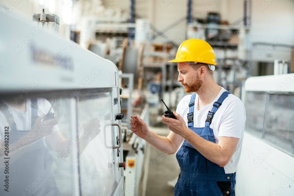 Man in uniform at factory talking on walkie-talkie Man in uniform at factory talking on walkie-talkie