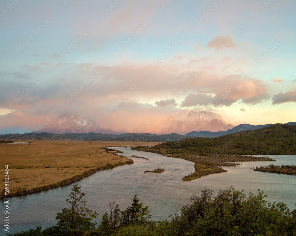 Pink colored sunrise over Torres del Paine mountains in Patagonia Chile.  With river in foreground 